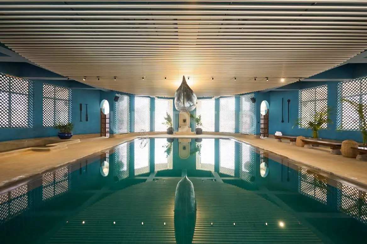 Indoor wellness pool with a boat suspended above the water at Kshemavana, Nelamangala